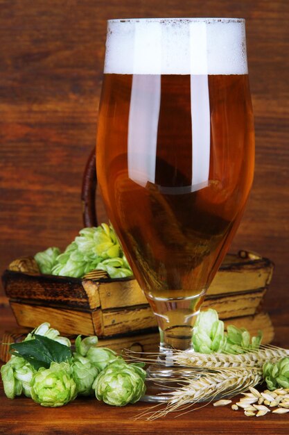 Copo de cerveja e lúpulo na mesa de madeira