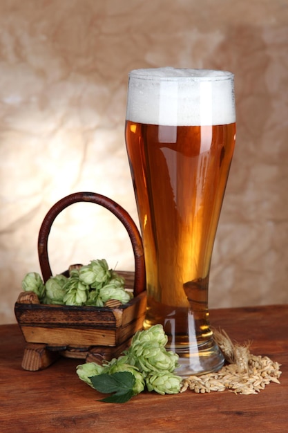 Copo de cerveja e lúpulo na mesa de madeira