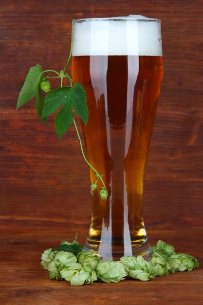 Copo de cerveja e lúpulo na mesa de madeira