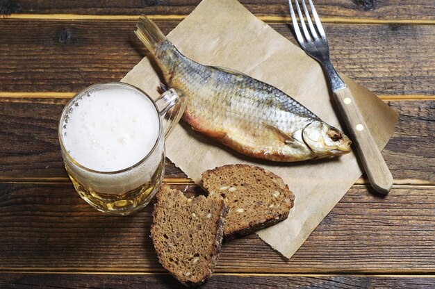 Copo de cerveja e peixe salgado seco na mesa de madeira