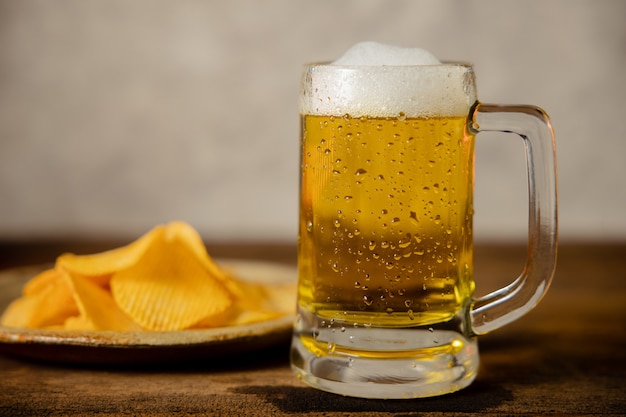 Copo de cerveja e prato com batatas fritas na mesa