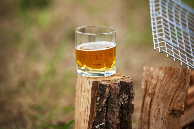 Copo de cerveja fica na lenha de madeira perto da grelha ao ar livre