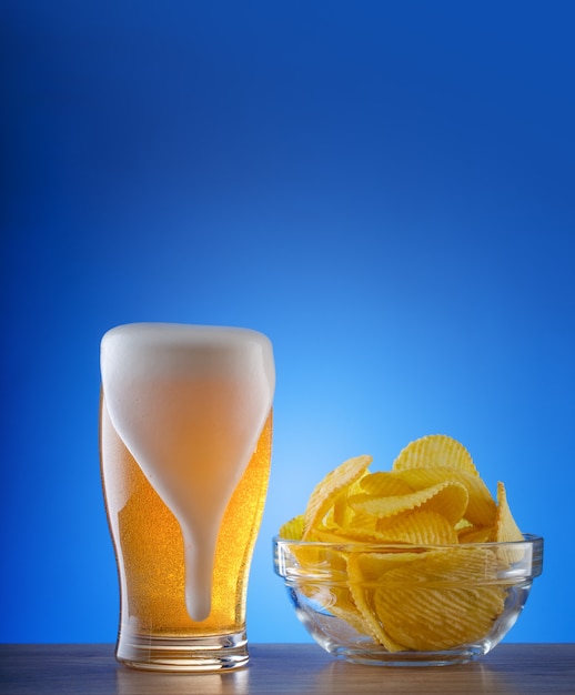 Copo de cerveja light com manchas de espuma e batatas fritas onduladas