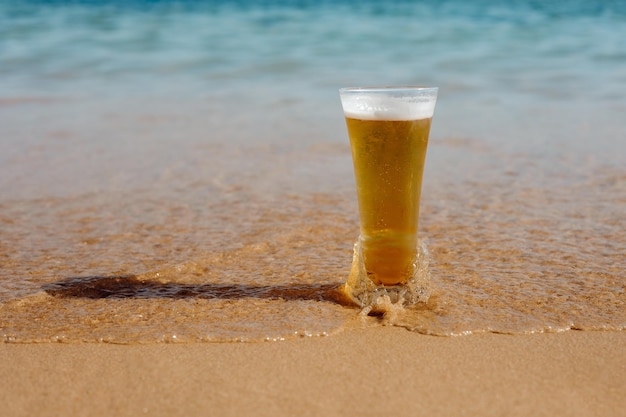 Copo de cerveja na praia um copo de cerveja com fundo do mar