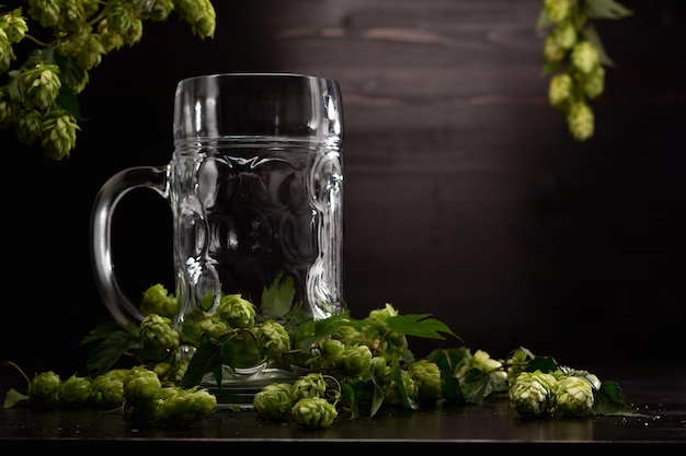 copo de cerveja vazio em fundo de madeira com lúpulo