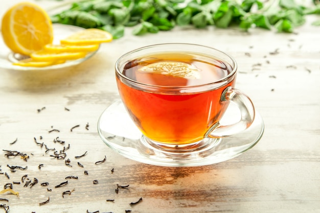 Copo de chá em uma mesa de madeira com fatias de limão.