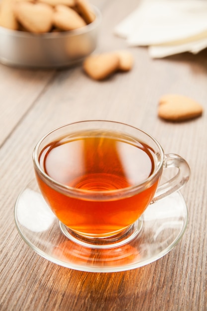 Copo de chá em uma mesa de madeira com uma caixa de biscoitos.