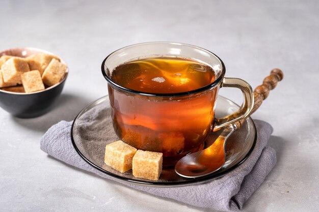 Foto copo de chá preto quente com cubos de açúcar em fundo claro