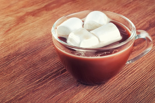 copo de chocolate quente com marshmallows em fundo de madeira marrom