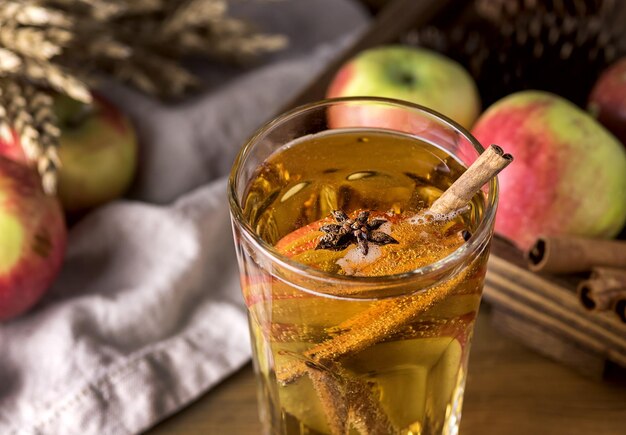 Foto copo de cidra saborosa com maçãs e especiarias em fundo de madeira rústica bebida de natal close-up
