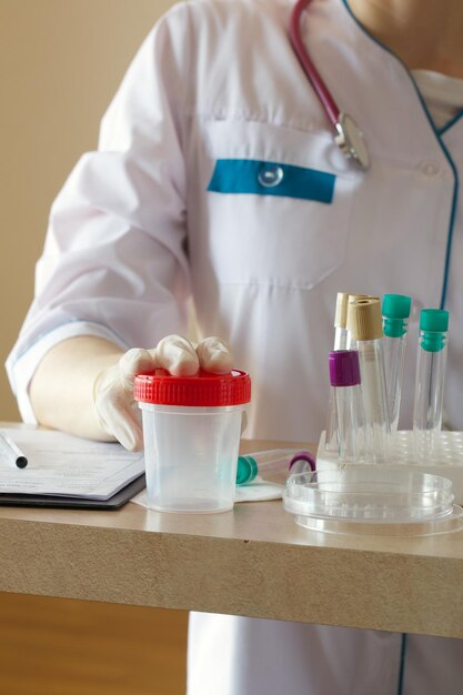 Copo de coleta para teste de urina na mesa de um técnico de laboratório.