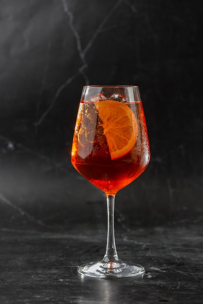 Copo de coquetel Aperol spritz gelado servido em taça de vinho decorada com fatias de laranja