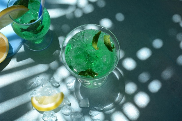 Copo de coquetel de fada verde com folhas de limão e hortelã Licor de menta refrescante doce com gelo e rum absinto Cubos de gelo e vodka