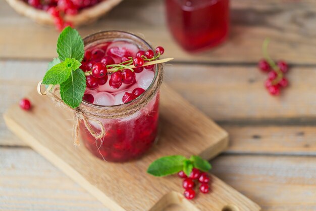 Copo de coquetel de groselha ou mocktail, bebida refrescante de verão com gelo picado e água com gás em uma madeira.