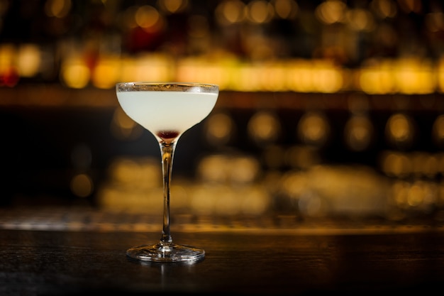 Copo de coquetel elegante de coquetel doce e azedo fresco no fundo desfocado da luz dourada no bar