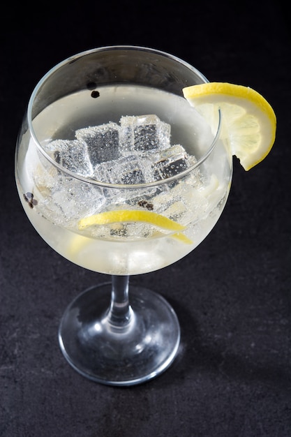 Copo de gin tônico com limão em fundo preto
