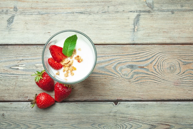 Copo de iogurte de morango saudável com frutas frescas na vista superior de mesa de madeira