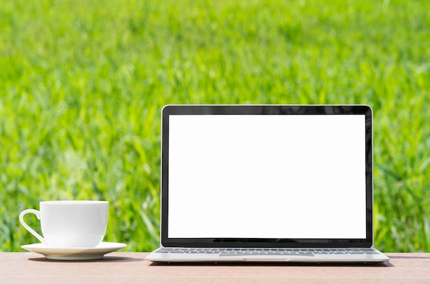 Copo de laptop e café em campo de grama verde de agente de prancha de madeira na zona rural