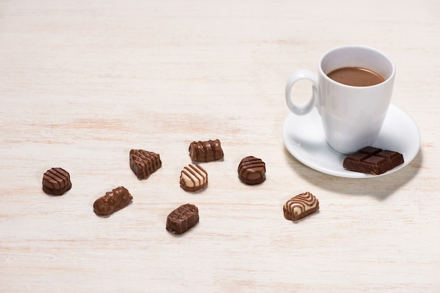 Copo de leite com chocolate e vários chocolates na mesa