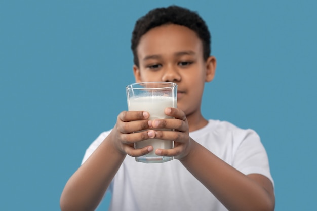 Copo de leite. Copo de leite nas mãos estendidas de um simpático estudante afro-americano numa foto de estúdio