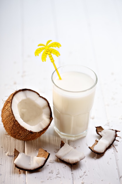 Copo de leite de coco na mesa de madeira branca