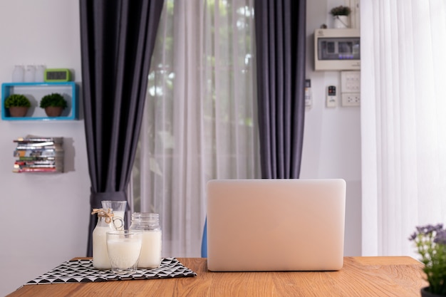 Foto copo de leite e laptop na sala de estar.