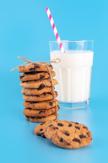 Copo de leite fresco com palha e biscoitos de chocolate marrom escola fundo azul Comida doce gostoso