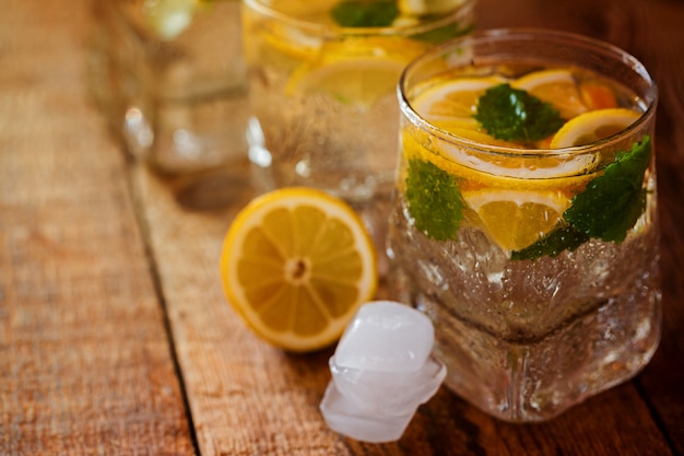 Copo de limonada com limão e hortelã no fundo de madeira