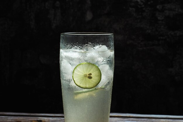 Copo de limonada gelada na mesa de madeira. Fundo escuro.