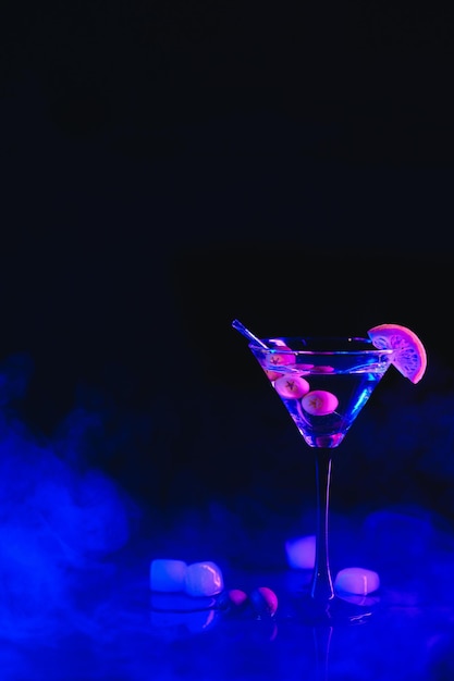 Copo de Martini e azeitonas em um fundo preto com luzes de neon