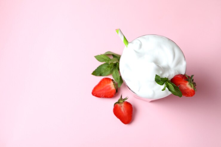 Foto copo de milkshake de morango e ingredientes em fundo rosa