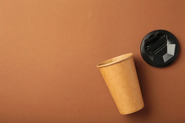 Foto copo de papel descartável em fundo marrom com espaço de cópia. conceito de café.