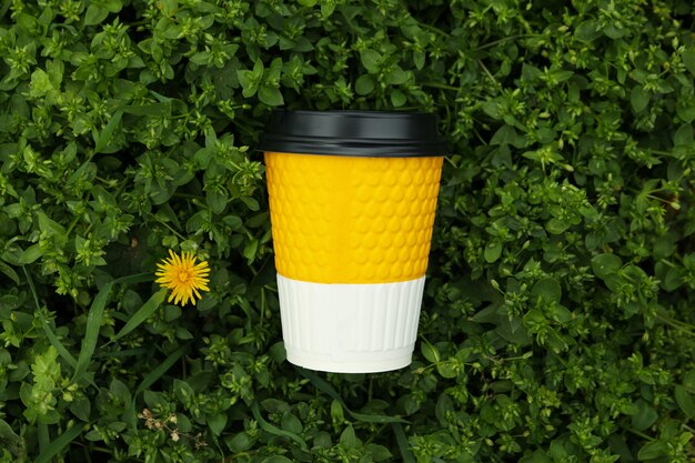 Copo de papel na grama verde fresca. Taça para bebida