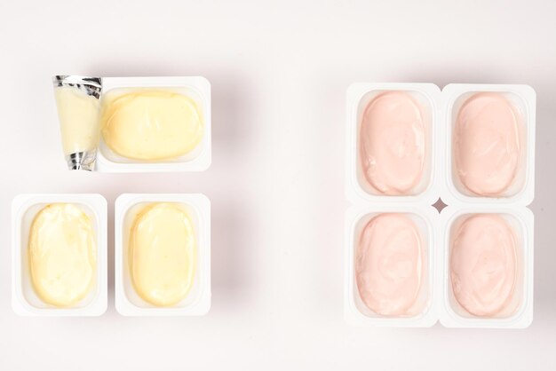 Copo de plástico com iogurte saboroso isolado em branco Vista superior Espaço para texto ou design