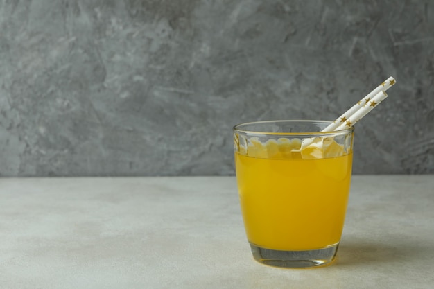 Copo de refrigerante de laranja na mesa texturizada branca contra a superfície cinza