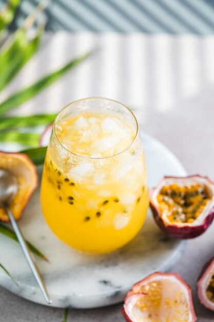 Foto copo de refrigerante gelado de maracujá com limão e meia fatia de maracujá em uma bebida refrescante de fundo claro ou bebida com gelo