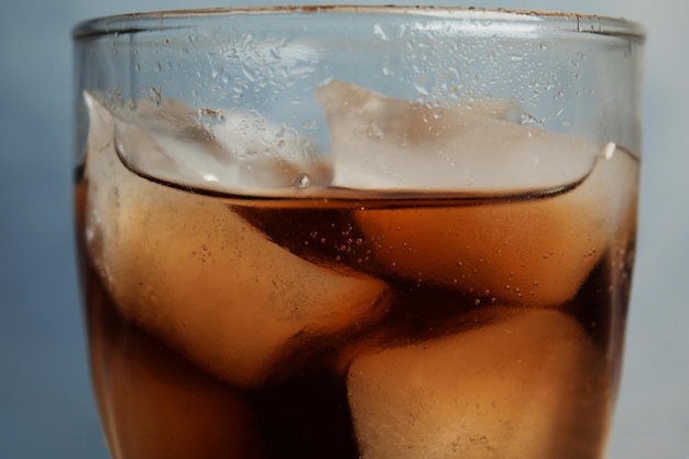 Foto copo de refrigerante refrescante com cubos de gelo em closeup de fundo azul