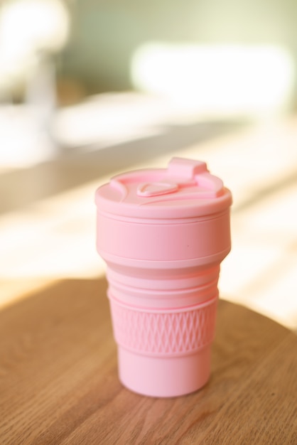 Copo de silicone dobrável rosa para bebidas sem plástico no estilo de zero desperdício em um ambiente interno, close-up.