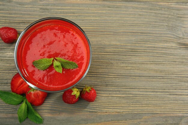 Copo de smoothie de morango com frutas na mesa de madeira close-up