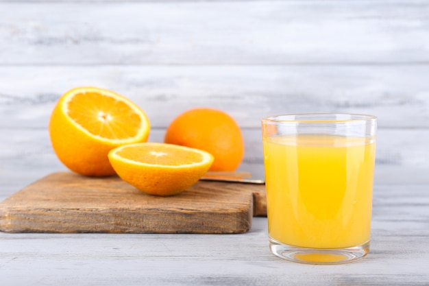 Copo de suco com laranja fresca na mesa de madeira cinza