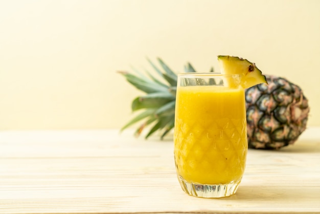 Copo de suco de abacaxi fresco na mesa de madeira