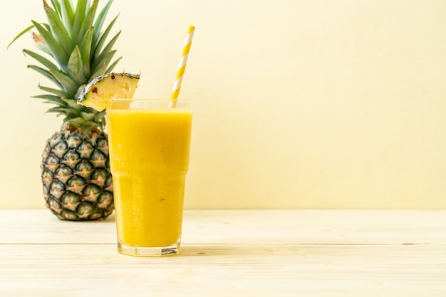 Copo de suco de abacaxi fresco na mesa de madeira