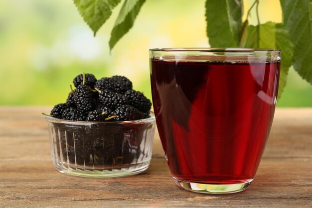 Copo de suco de amora refrescante com frutas em fundo brilhante