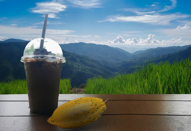 Copo de suco de cacau no fundo de montanhas e céu azul