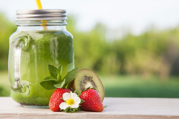 Copo de suco de desintoxicação e frutas na mesa de madeira no jardim com frutas