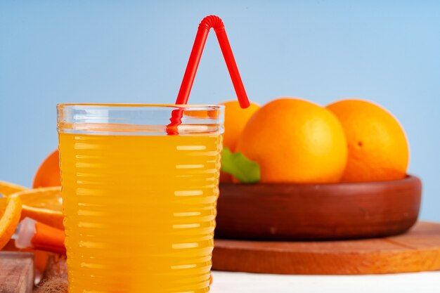 Copo de suco de laranja com canudo vermelho na mesa