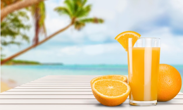 Copo de suco de laranja delicioso no fundo da praia