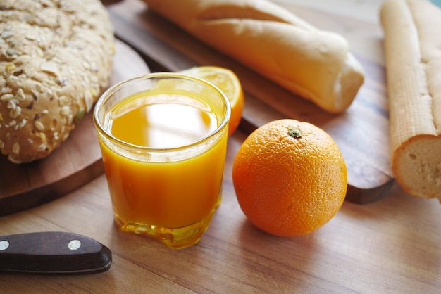 Copo de suco de laranja e pão integral na mesa