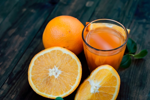 Copo de suco de laranja e um grupo de laranjas no quadro escuro