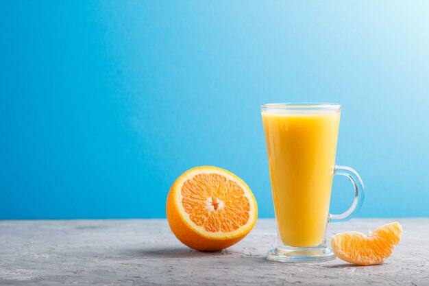 Copo de suco de laranja em um fundo cinza e azul. Vista lateral